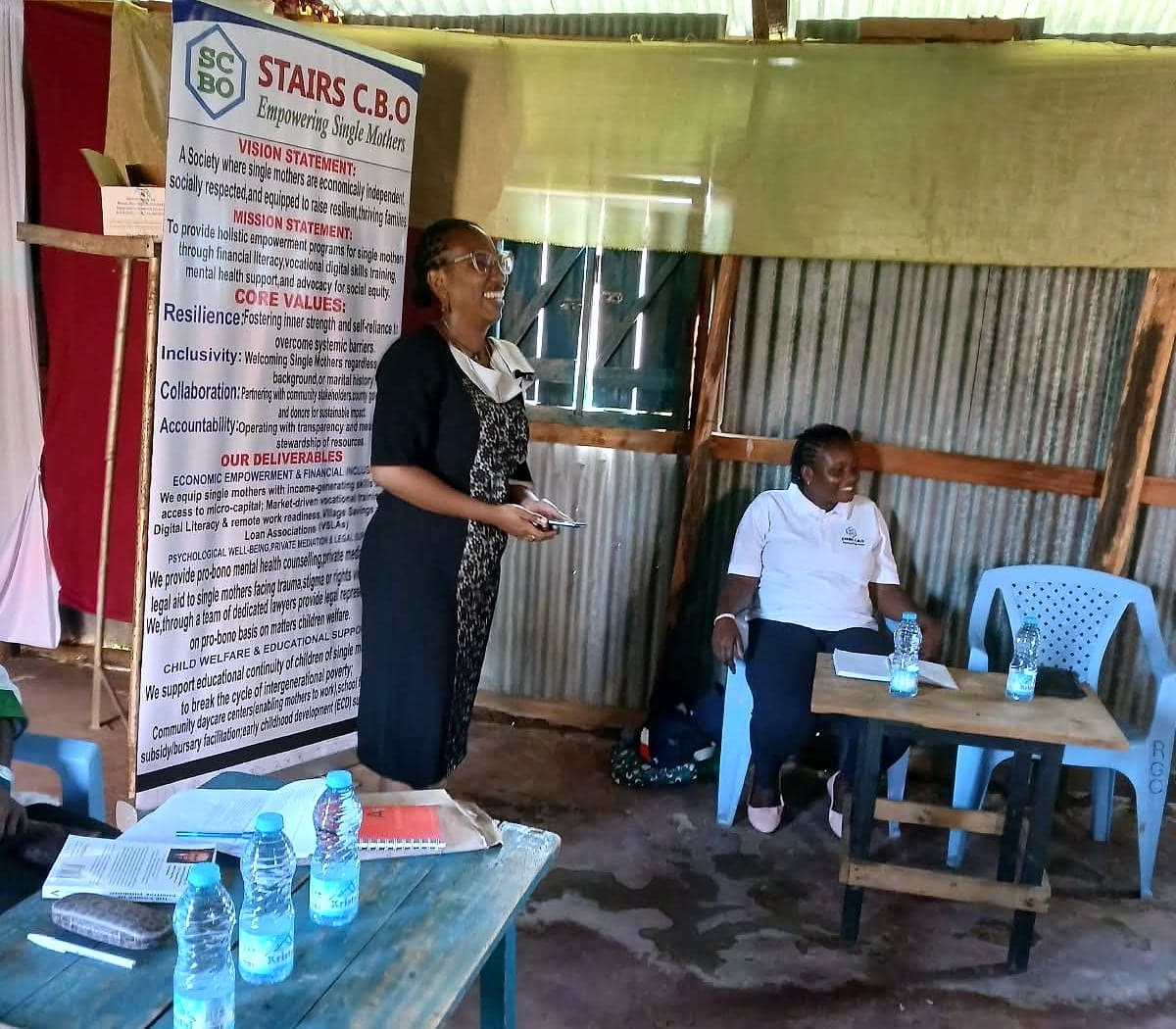 A speaker laughing with the group beside the STAIRS banner during a training session