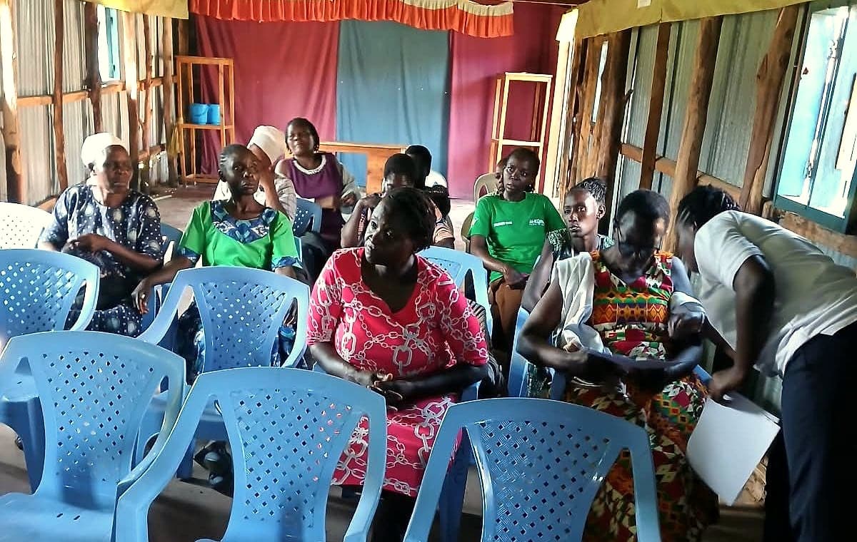 A STAIRS team member going through papers with women seated at a weekly skills training session